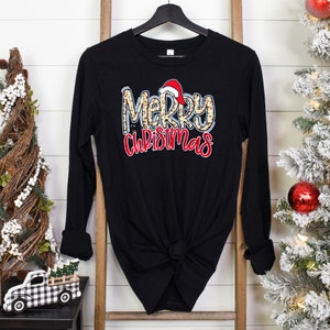May include: Black long-sleeve shirt with a leopard print "Merry Christmas" graphic with a red Santa hat on the "M".