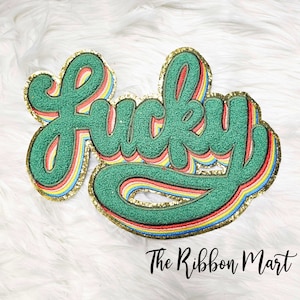 May include: A green "Lucky" word patch with a rainbow border and gold glitter. The patch is made of felt and is perfect for adding a touch of whimsy to any project.