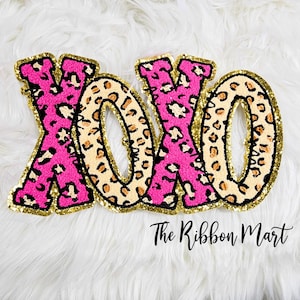 May include: Pink and brown "XOXO" letters with a leopard print design and gold glitter accents.
