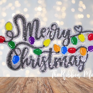 May include: A sparkly black and silver applique with the words "Merry Christmas" and a string of colorful lights.
