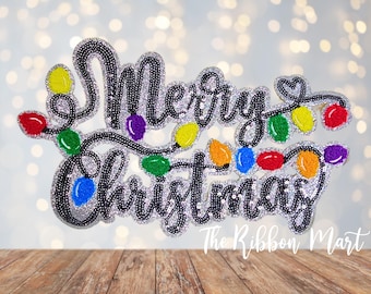 May include: A sparkly black and silver applique with the words "Merry Christmas" and a string of colorful lights.