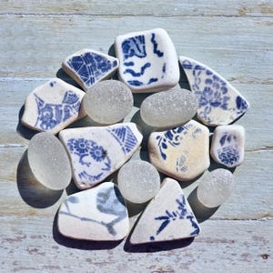 Può includere: Una collezione di frammenti di vetro marino e ceramica lisci e usurati. I pezzi di ceramica sono bianchi con vari motivi blu, inclusi disegni floreali e geometrici. I pezzi di vetro marino sono traslucidi, opachi e di forma arrotondata.