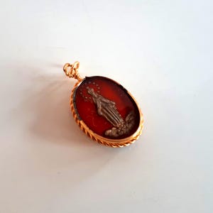 Colgante con medalla antigua rara bañada en oro y esmalte rojo en burbuja de vidrio con la Santísima Virgen María y elementos religiosos de la iglesia.