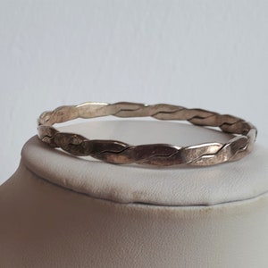 Peut inclure: Un bracelet jonc en argent tressé. Le bracelet est fait d'un fil d'argent épais et torsadé.