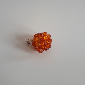 Peut inclure: Un pendentif rond composé de perles d'ambre.