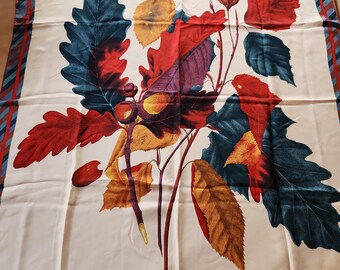 May include: A white silk scarf featuring a colourful floral print of red, yellow, green and purple leaves. The scarf has a red, blue and brown striped border with the text "Perry Ellis" in the bottom right corner.