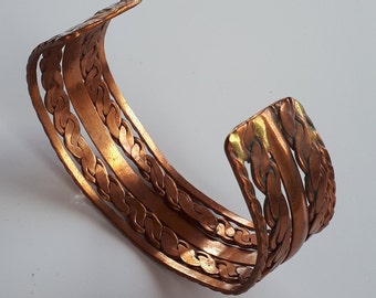 Peut inclure: Un bracelet en cuivre avec un motif tressé. Le bracelet est composé de trois brins de fil de cuivre qui sont entrelacés pour créer un motif complexe. Le bracelet a un accent doré sur le dessus.