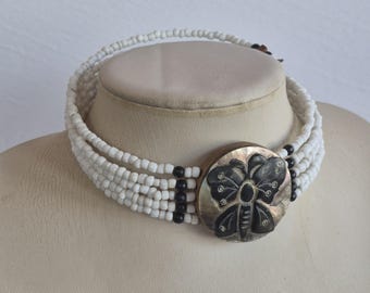 Collar gargantilla estilo boho vintage con semillas de cristal blanco talladas en nácar y forma de mariposa.