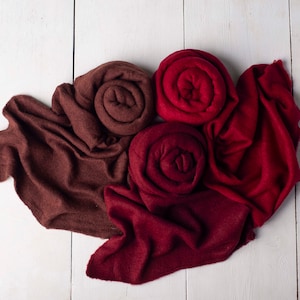 Peut inclure: Deux rouleaux de tissu, un brun et un bordeaux, disposés en cercle sur une surface en bois blanc. Les rouleaux de tissu sont doux et moelleux, et ils sont parfaits pour ajouter une touche de chaleur et de couleur à n'importe quelle pièce.