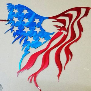 Puede incluir: Arte de pared de metal con un águila calva americana con las alas extendidas en forma de bandera estadounidense. El águila es roja y la bandera es azul con estrellas blancas.