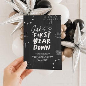 May include: A rectangular black invitation card with white text reading Jake's FIRST YEAR DOWN, including event details for a toddler tailgate party on Saturday, October 15 at 1:00 PM at 10456 Tevan Road East, NC, with RSVP to Alex at 540.444.7890.