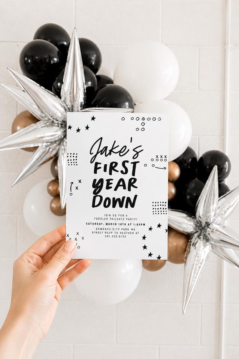 May include: A white rectangular invitation card with black text reading Jake's FIRST YEAR DOWN, Join us for a toddler tailgate party, Saturday, March 10th at 1:00pm, Edmonds City Park WA, Kindly RSVP to Heather at 301.220.0133, with star and dot graphics.