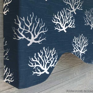 May include: A navy blue fabric window valance featuring a repeating white coral branch pattern. The valance has a scalloped bottom edge and is constructed from Isadella in Premier Navy fabric, displaying a textured weave throughout the material.