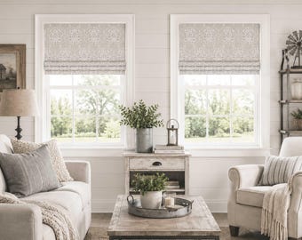 May include: Two windows featuring light beige and white fabric roman shades with a repeating damask pattern. The shades are mounted inside the window frames, covering the upper portion of the glass while allowing natural light to enter below.