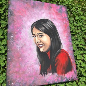 May include: A painting of a woman with long black hair, wearing a red shirt, against a pink and purple galaxy background. The painting is signed "Michelle".