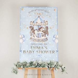 Könnte beinhalten: Ein blaues und goldenes Willkommens-Schild für eine Babyparty mit einer Karussell-Illustration und dem Text "Round and round we go" und "Willkommen zur Babyparty von Emma".
