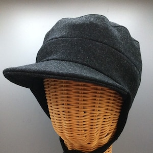 May include: A black wool cap with a wide brim and a tie that can be tied under the chin. The cap has a textured surface and a simple design.