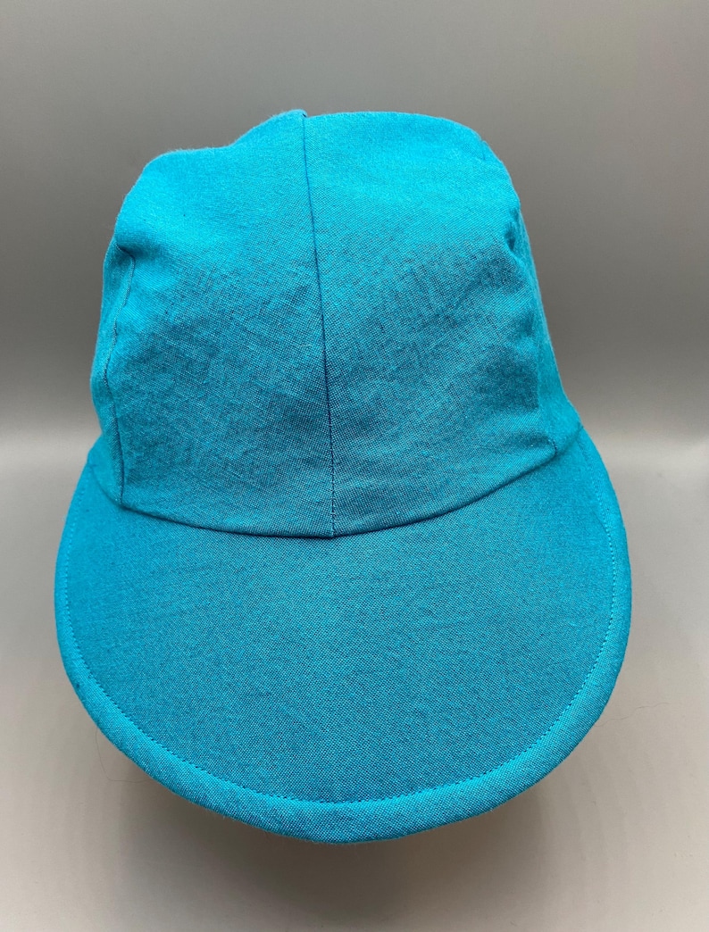 May include: A turquoise baseball cap with a curved brim. The cap is made of a textured fabric and has a classic six-panel design. The brim is a solid color, and the cap appears to be unworn.