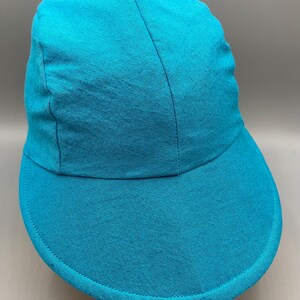 May include: A solid turquoise baseball cap with a curved brim. The cap is made of a soft fabric and has a structured crown. The brim is stitched around the edge. The cap is a solid color and has a simple design.