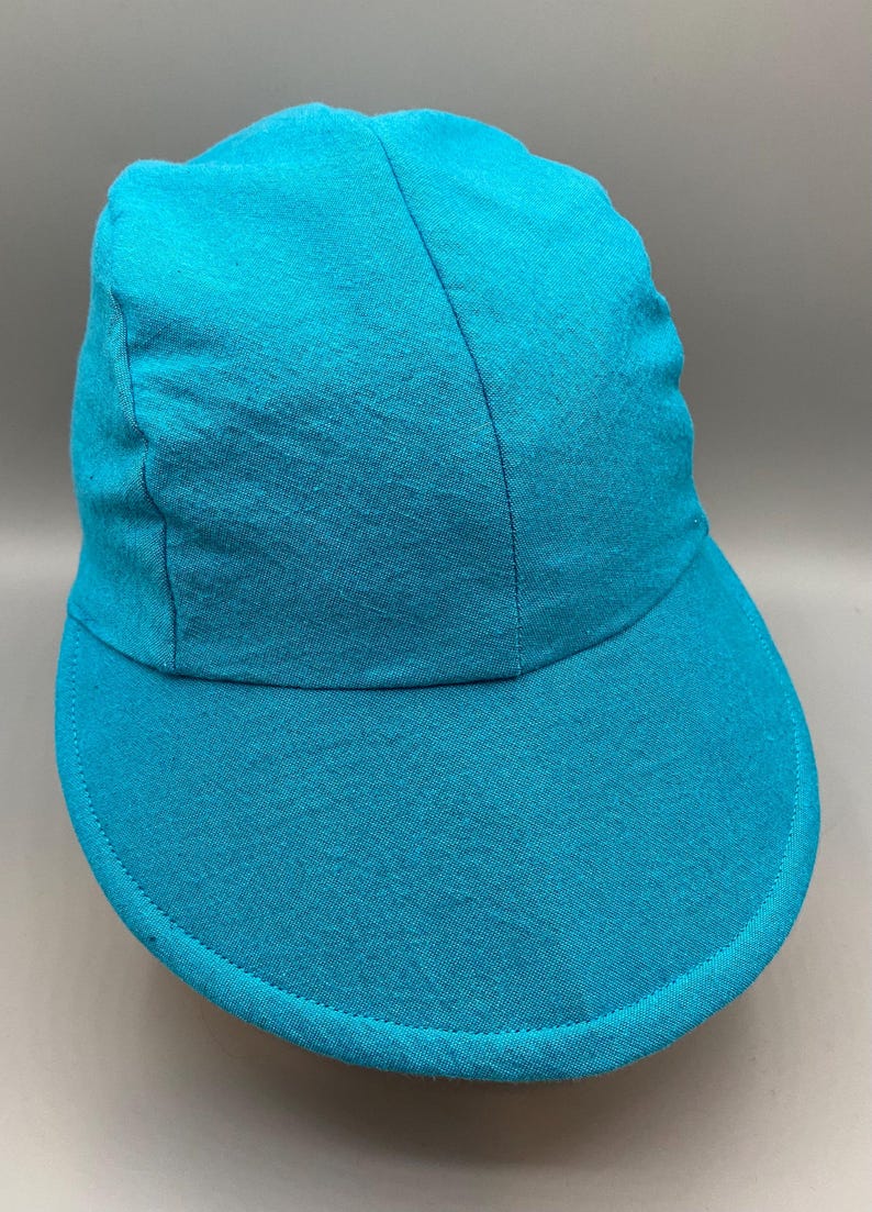 May include: A solid turquoise baseball cap with a curved brim. The cap is made of a soft fabric and has a structured crown. The brim is stitched around the edge. The cap is a solid color and has a simple design.