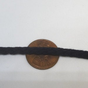 May include: Black cotton cord, approximately the size of a US penny.