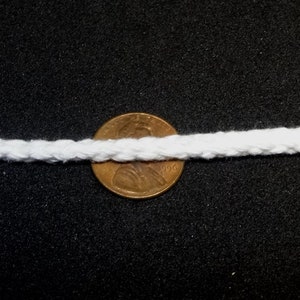 May include: White cotton rope with a diameter of about 1/2 inch, shown next to a US penny for scale.
