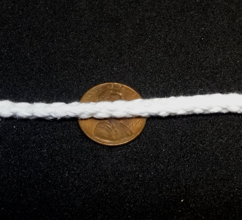May include: White cotton rope with a diameter of about 1/2 inch, shown next to a US penny for scale.