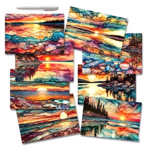 May include: A collection of eight rectangular art prints featuring vibrant, abstract landscape scenes of sunsets over water, forests, and rocky shorelines in shades of orange, blue, purple, and yellow, accompanied by a silver metal pen at the top.
