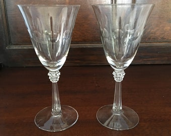 May include: Two clear glass wine glasses with a textured stem and a round base.