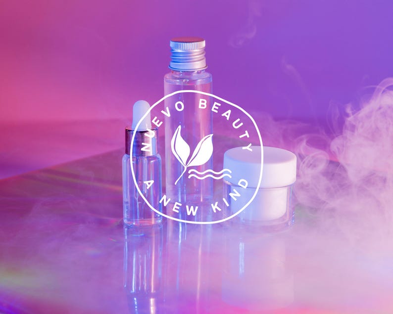 May include: Three clear glass bottles with a white label that says "Evo Beauty A New Kind" in a circle. The bottles are on a iridescent surface with a pink and purple background. There is white smoke in the background.