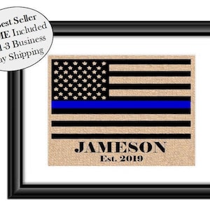 May include: A burlap American flag with a blue line, personalized with the name "JAMESON" and the text "Est. 2019".