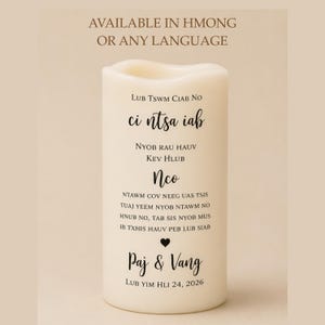 Peut inclure: Une bougie pilier blanche avec un dessus ondul&eacute;, avec du texte noir en police script. La bougie comprend les noms "Paj & Vang" et la date "LUB YIM HLI 24, 2026". Le texte "AVAILABLE IN HMONG OR ANY LANGUAGE" est en haut.