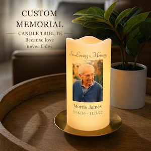 May include: A custom memorial candle tribute with the text "CUSTOM MEMORIAL" and "CANDLE TRIBUTE." The candle has a photo of a person with the text "In Loving Memory" and the name "Morris James" with dates. The candle sits on a gold-colored plate.