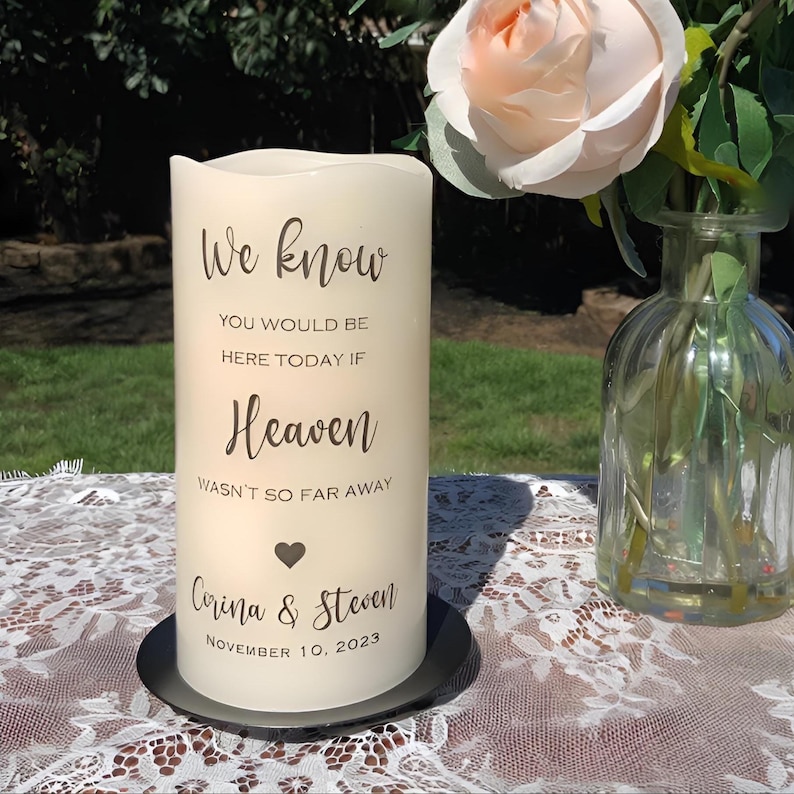 Peut inclure: Une bougie pilier cr&egrave;me avec le texte "We know, You would be here today if Heaven wasn't so far away." La bougie comprend les noms "Corina & Steven" et la date "November 10, 2023." La bougie repose sur une plaque noire.