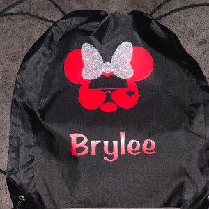 May include: Black drawstring bag with a red and silver glitter Minnie Mouse design and the name "Brylee" printed in pink.