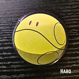 Puede incluir: Un bot&oacute;n redondo con una cara amarilla, l&iacute;neas negras curvas y dos ojos rojos. El bot&oacute;n tiene un borde negro y la palabra "HARO" en texto blanco en la parte inferior. Sobre un fondo negro.