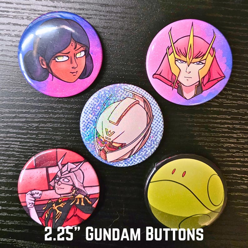 Puede incluir: Cinco botones Gundam de 5,7 cm de di&aacute;metro, con dise&ntilde;os de personajes de anime coloridos. Los botones presentan ilustraciones detalladas y colores vibrantes, sobre un fondo oscuro. El texto "2.25" GUNDAM BUTTONS" se muestra en la parte inferior.