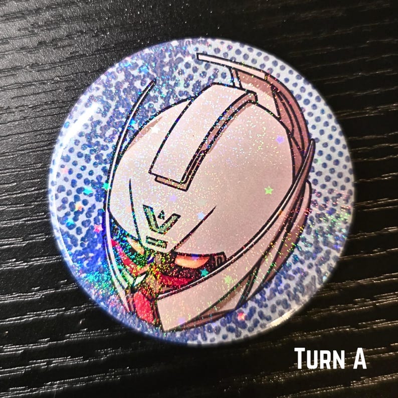 Puede incluir: Bot&oacute;n redondo con un dise&ntilde;o hologr&aacute;fico y brillante. El bot&oacute;n presenta una ilustraci&oacute;n blanca y rosa de una cabeza de robot con el texto "TURN A" en la parte inferior. El fondo es azul claro con peque&ntilde;os puntos.