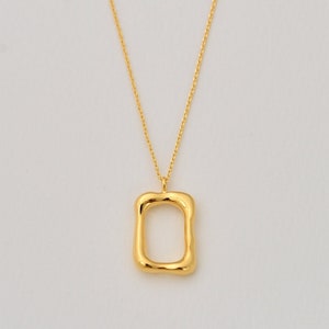 May include: A gold chain necklace with a gold, irregular, rectangular pendant.