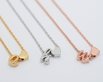 May include: Three delicate necklaces with a heart charm and a letter pendant. The necklaces are gold, silver, and rose gold.