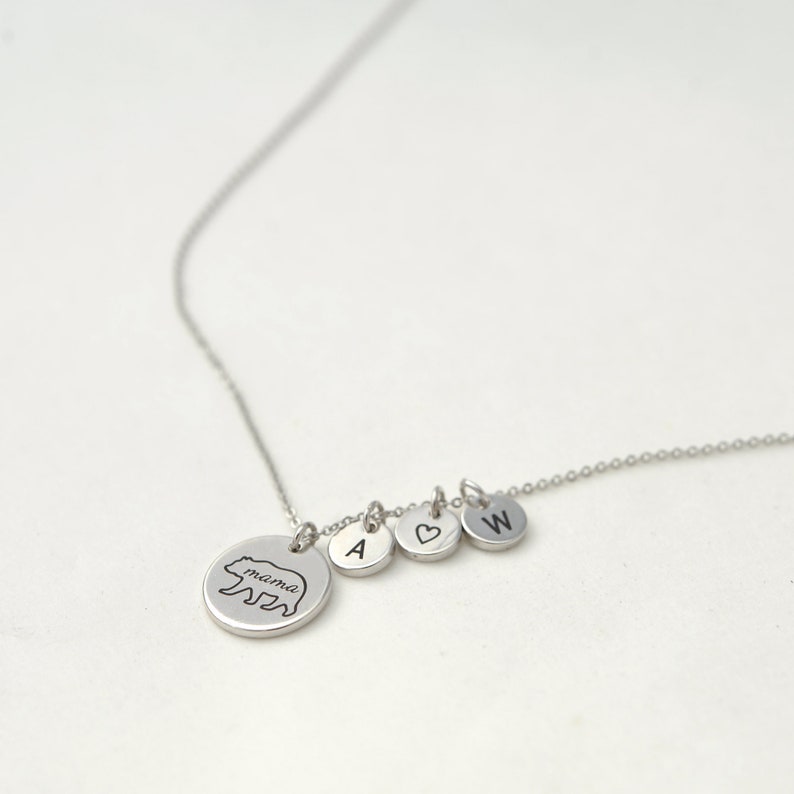 May include: A silver necklace with a bear charm that says "mama" and three other charms: a heart, the letter A, and the letter W.