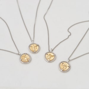 May include: Four silver necklaces with gold coin pendants featuring different designs. The coins are suspended in a silver frame.
