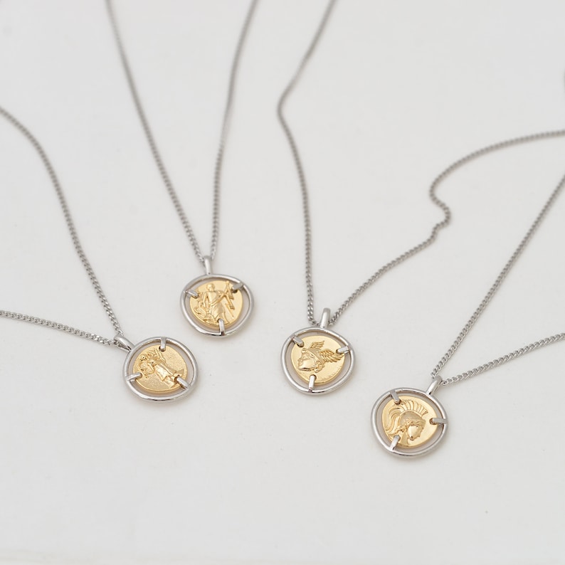 May include: Four silver necklaces with gold coin pendants featuring different designs. The coins are suspended in a silver frame.