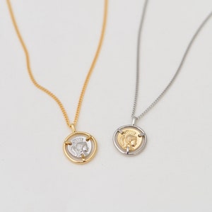 May include: Two gold necklaces with a coin pendant featuring a profile of a warrior with a helmet. One necklace has a gold chain and the other has a silver chain.
