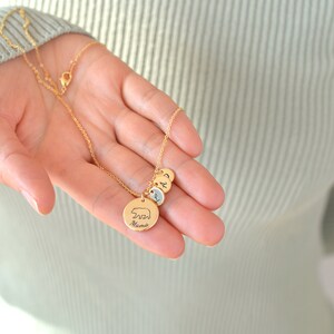 May include: Gold necklace with a bear charm and the word "Mama" engraved on it. The necklace also has three smaller charms with the letters A, B, and C.