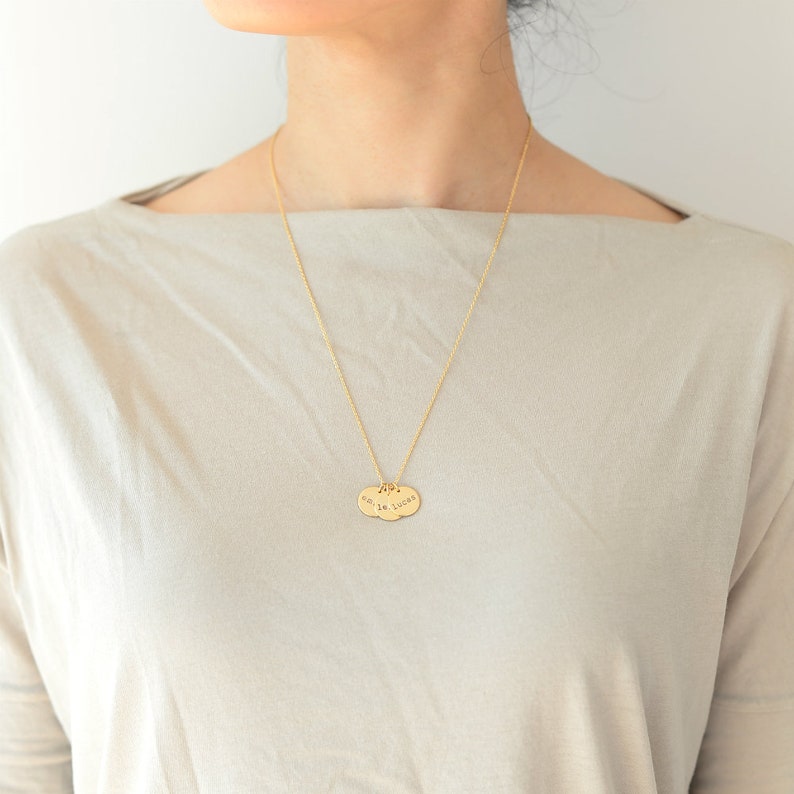 Op de afbeelding: Een gouden ketting met twee ovale hangers. De hangers zijn gegraveerd met de woorden "smile" en "lucky".