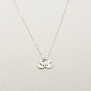 Op de afbeelding: Zilveren ketting met twee ronde hangers, een gegraveerd met "Brendan" en de andere met "Thomas".