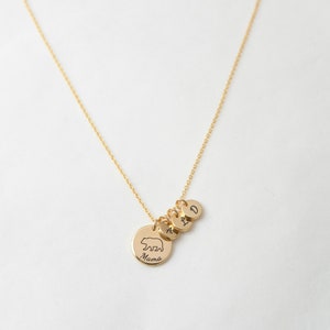 May include: Gold necklace with a bear charm and three initial charms. The bear charm says "Mama" on the back. The initials are A, I, and D.