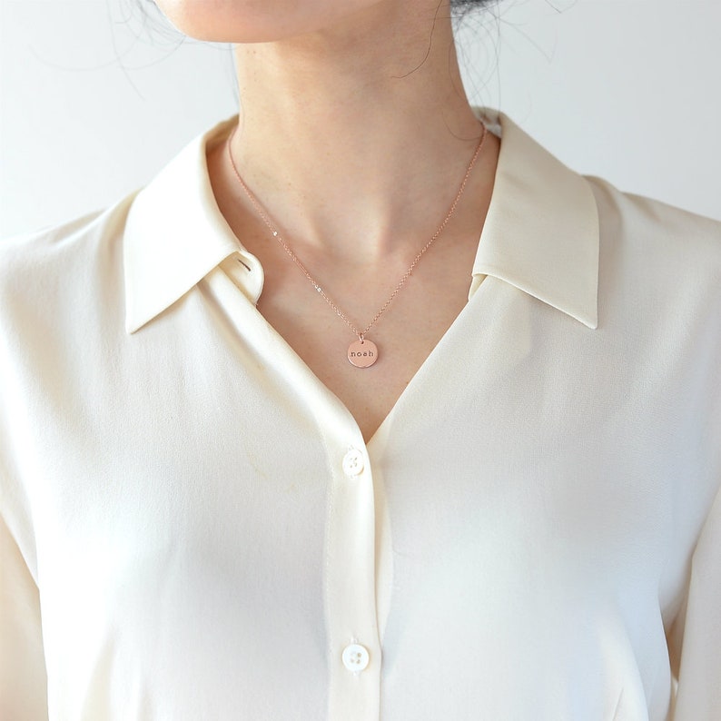 Op de afbeelding: Een ketting van ros&eacute;goud met een ronde hanger waarop "noah" staat.
