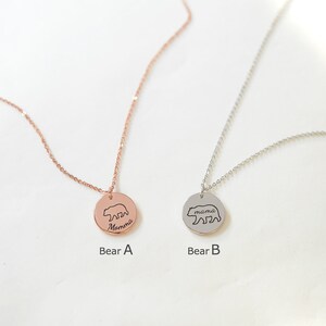 May include: Two silver necklaces with bear pendants. The pendant on the left is rose gold and says "Momma" with a bear outline. The pendant on the right is silver and says "mama" with a bear outline.